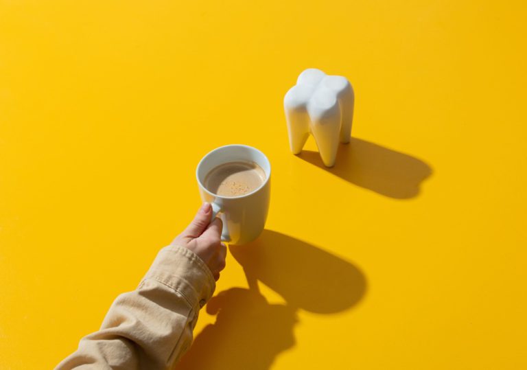 female hand holds cup of coffee next to tooth on y 2022 05 01 23 35 44 utc