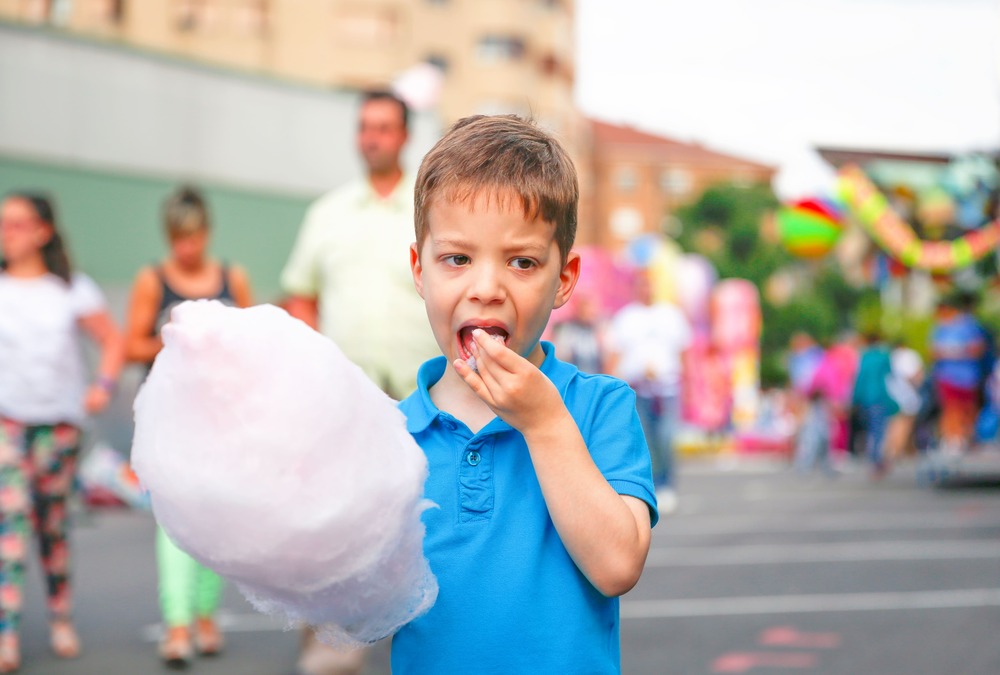 cute kid eating cotton candy over fair background 2021 09 01 02 03 24 utc