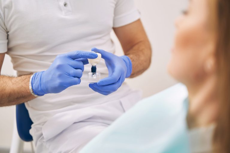 dentist showing tooth implant to woman in clinic 2022 03 25 18 00 23 utc