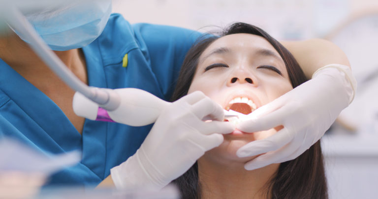 woman doing scaling and root planing in dental cli utc