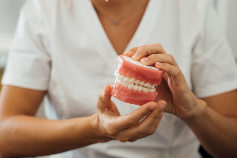 partial view of a nurse holding dentures in hands 2023 11 27 05 06 59 utc 1